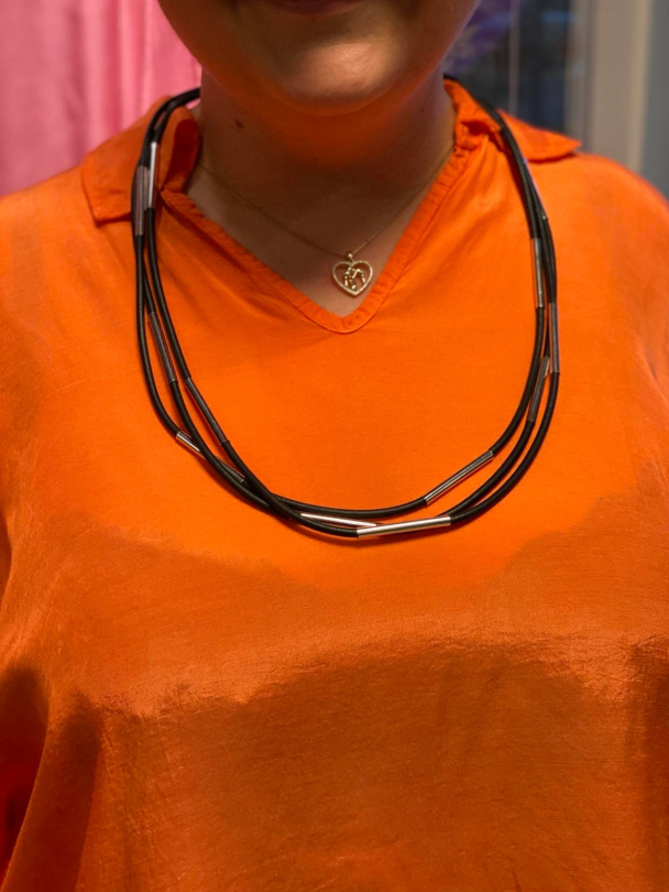 Sort smykke i gummi med sølvdetaljer