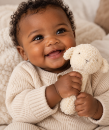 Smilende baby med lammebamse.png